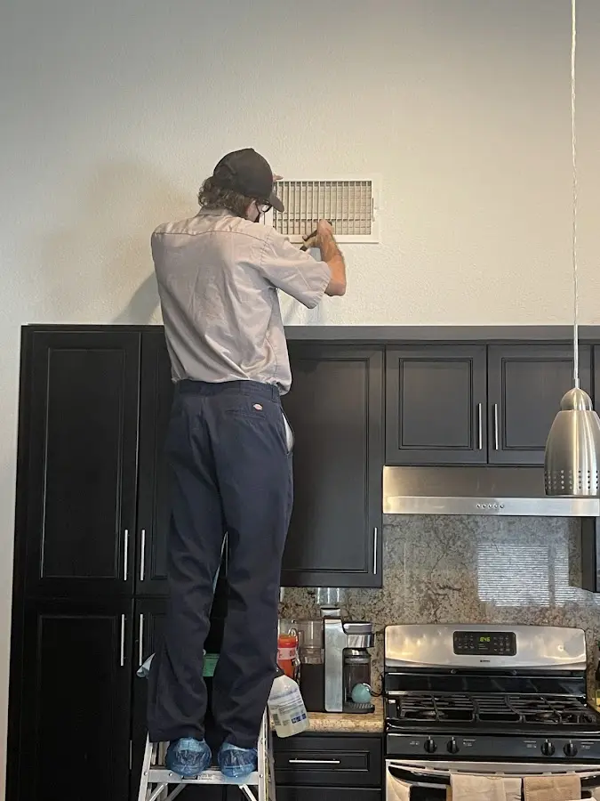 Technician inspecting an air vent during HVAC service in Erlanger
